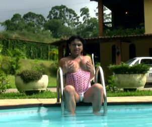 Ladyboy in rosy harness fools around the pool and wanks off