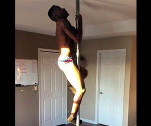 Dark-hued male stripper rolling on a pole.