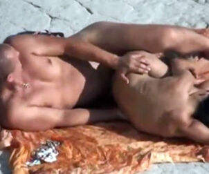 naturist duo having romp on the ebony seaside